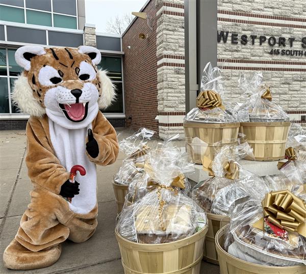  A wildcat mascot poses next to baskets of food.